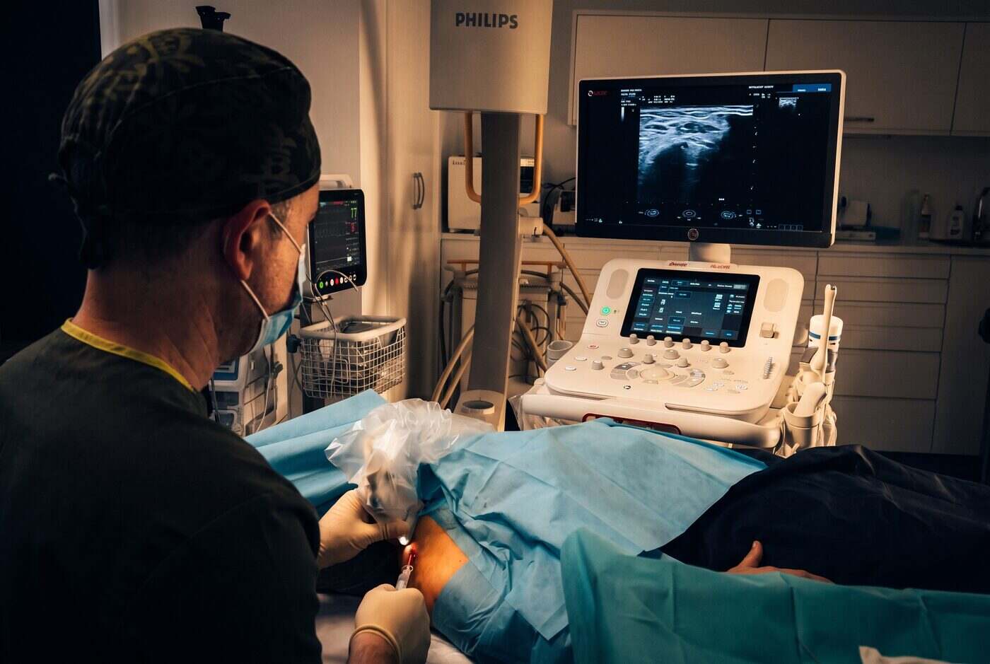 El Dr. Martín Rodríguez Banqueri realizando una infiltración ecoguiada en la sala de intervencionismo de Clínica Dolentia; en el monitor del ecógrafo, la imagen de ultrasonido que guía la aguja en tiempo real