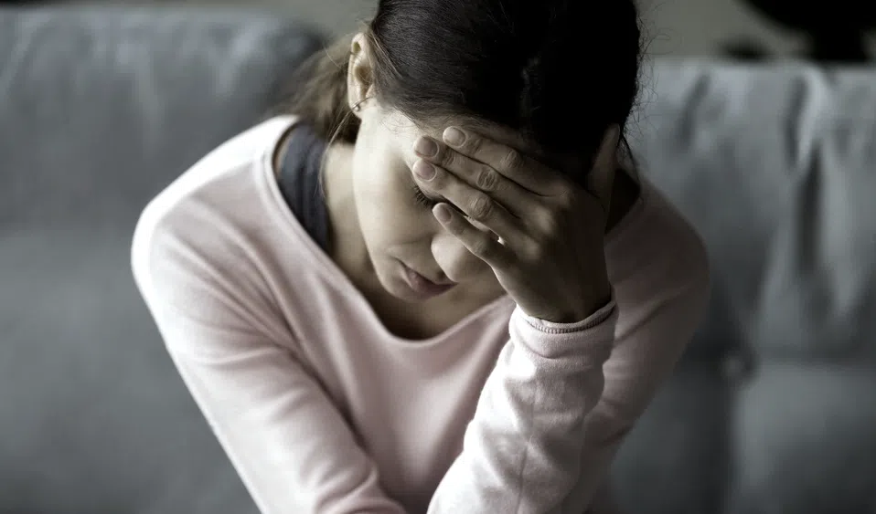 ujer mostrando signos de estrés o ansiedad, con la mano en la cabeza, un reflejo de las dificultades emocionales tratadas en la unidad de psicología clínica.